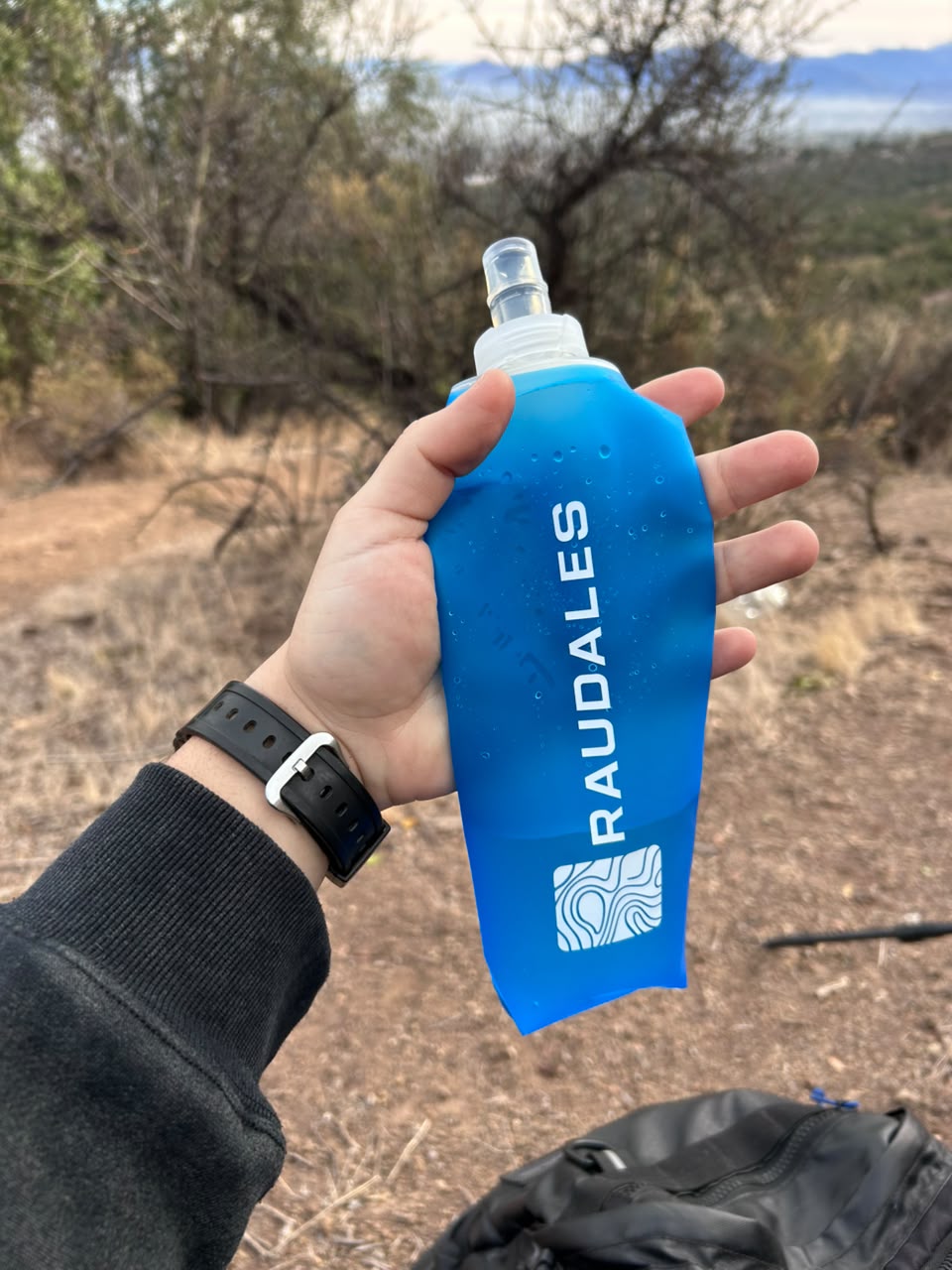 Soft Flask Azul 500 de RAUDALES sostenida en la mano en plena montaña